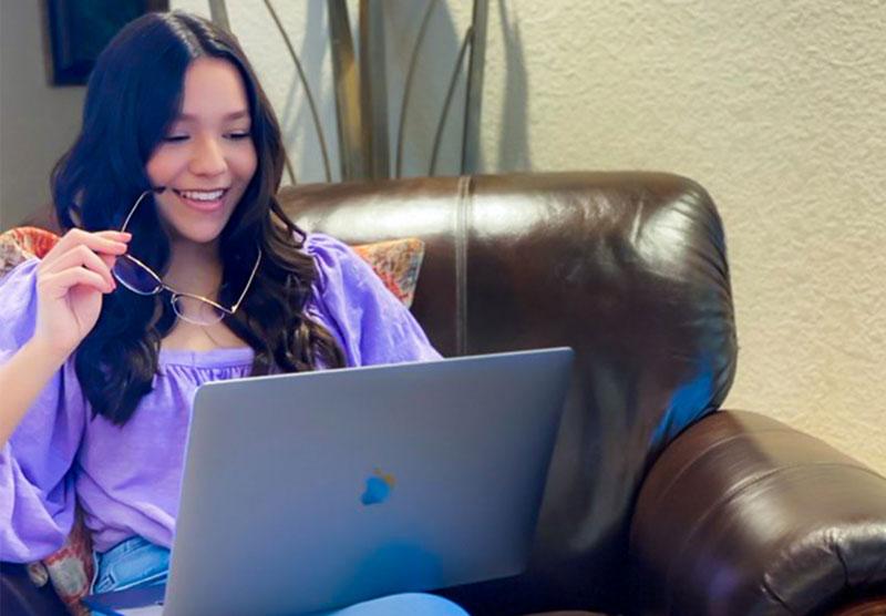 female student sitting on sofa looking at laptop