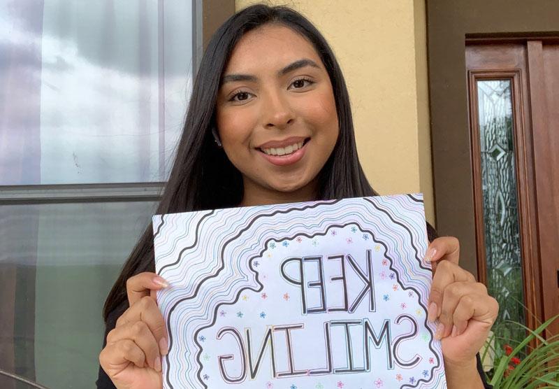 female student holding a keep smiling sign